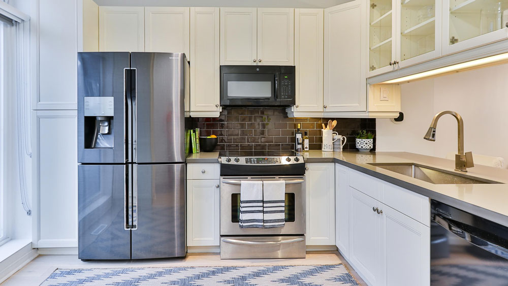 Kitchen with white cabinets, a refrigerator, microwave, electric stove, and dishwasher